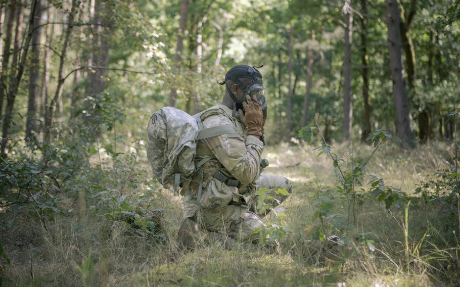 A soldier adjusts his mask.