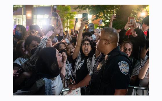 Protesters lock arms after breaking through barricades to enter the University Yard encampment at George Washington University in Washington on Sunday. MUST CREDIT: Jordan Tovin for The Washington Post
