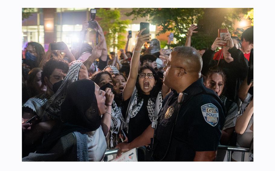 A police officer looks on as protesters shout after breaking through barricades to enter the University Yard encampment at George Washington University in Washington on Sunday, April 28, 2024.