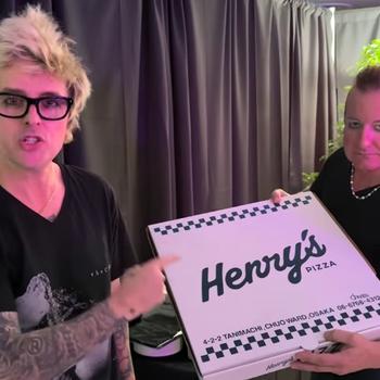 Two men hold a pizza box with “Henry’s” printed on it.