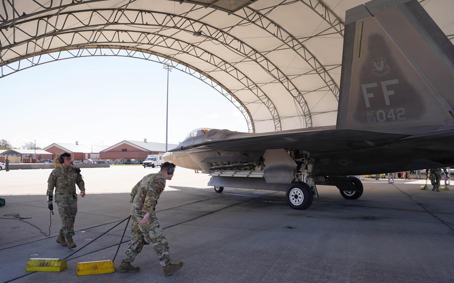 U.S. Airman 1st Class Cyede Khbais, 27th Fighter Generation Squadron crew chief, and Capt. Trent Amerson, 71st Fighter Generation Squadron commander, prepare to put chalks under one of the first two 71st Fighter Squadron F-22s to arrive at Joint Base Langley-Eustis, Va., Wednesday, March 29, 2023.