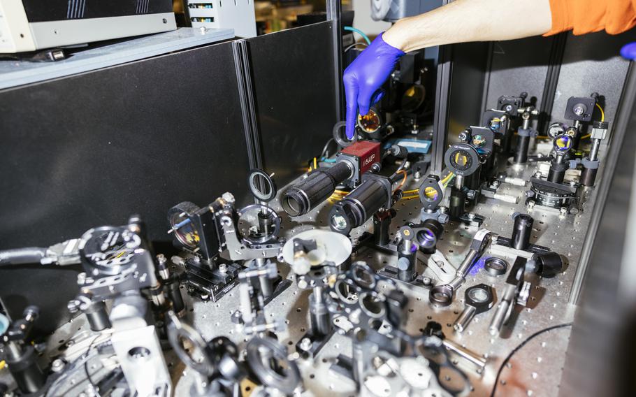 Graduate student Cyrus Zeledon points to a "home-built" specialized microscope in the quantum computing lab at the University of Chicago's Eckhardt Research Center on Oct. 4, 2022. 