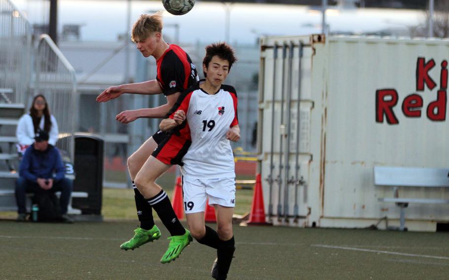 Yokohama International's Cameron Maine heads the ball in front of Nile C. Kinnick's Luis Galloway during Wednesday's boys soccer match. The Red Devils won 4-2.