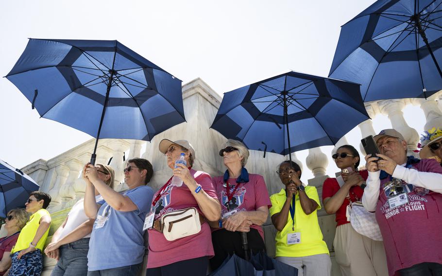 Female veterans stand together and hold blue umbrellas
