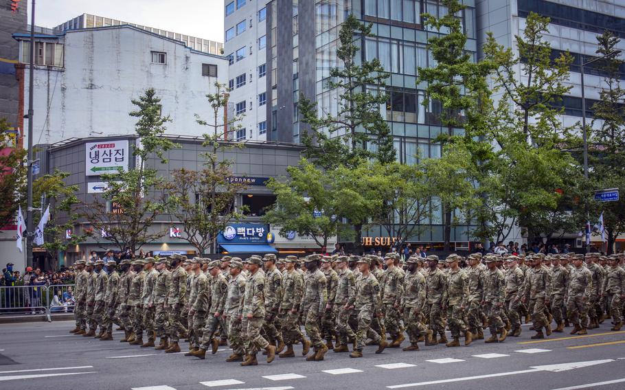 Hundreds of U.S. soldiers wearing uniforms march down the street in Seoul.