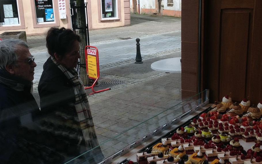 Passers-by check out the pastries in the window at Patisserie Rebert in Wissembourg, France.

