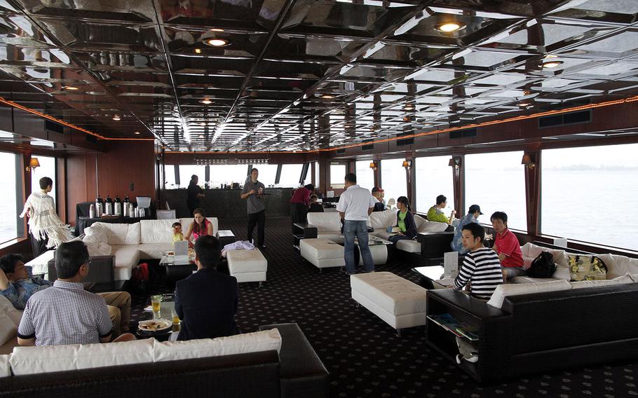 Passengers aboard the Majestic relax inside the enclosed top-level deck during a whale-watching excursion.