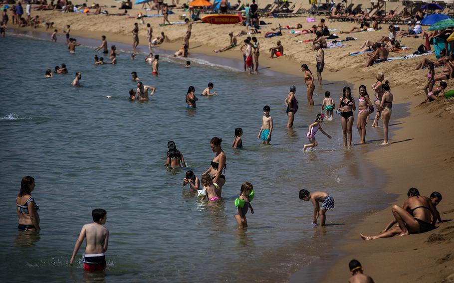 People cool off in the shallows June 29 at the beach in Barcelona, Spain. There are many spots in Europe where beaches lie close to city outings. 