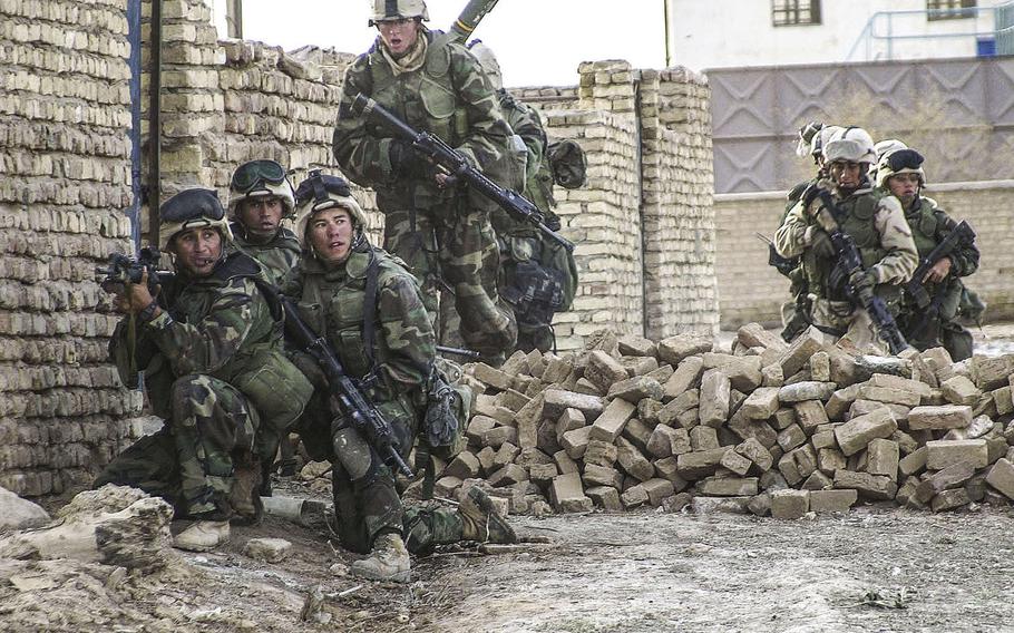 Marines from Golf Company, 2nd Battalion, 23rd Marines stack along a wall to provide cover fire during a raid on a local Baath Party headquaters building in Al Fahr, Iraq, in March 2003. The raid turned up a cache of weapons, intelligence documents and several Baath Party leaders taken prisoner.