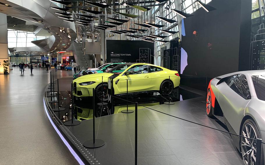 A yellow BMW M4 sits on display beside a prototype of the BMW Vision M Next electric sports car on the main floor of the BMW Welt in Munich, Germany. The museum features new cars BMW is slated to release to the public. The BMW Welt is scheduled to be closed until at least March 7 because of coronavirus prevention measures. 