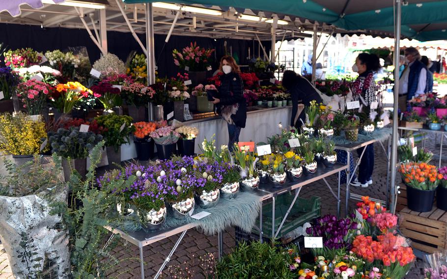 People stand back from each other to respect the coronavirus rules at a flower stand at Wiesbaden's farmers' market on March 3, 2021.