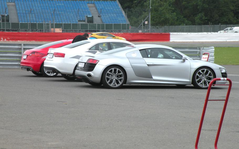 An Audi R8, and two other vehicles wait for passengers to take them around the track at during one of Silverstone Circuit's driving experiences. The longest straightaway on Silverstone's south loop, Hangar Straight, is the ideal place to test the car's 525 horsepower.