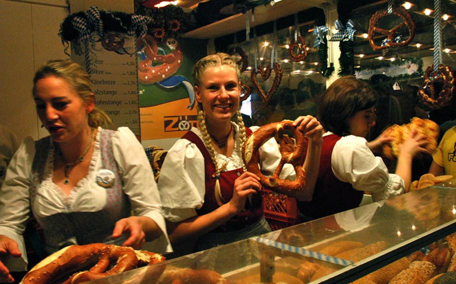 Oktoberfest staples: A woman wearing a dirndl holds up a large, soft pretzel.