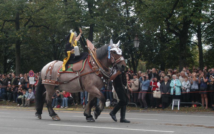 Crowds outside the Theresienwiese festival area greet the procession of Oktoberfest landlords and breweries, led as always by the Münchner Kindl, a girl in monk's costume riding horseback with a beer in hand.