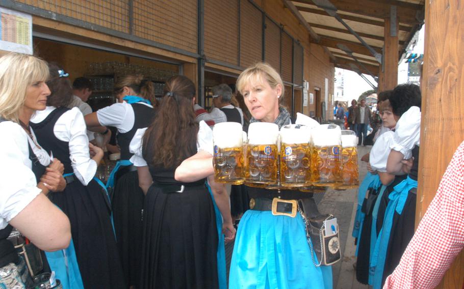 A woman, wearing a dirndl, carries several liters of beer to thirsty customers at the Löwenbräu tent.