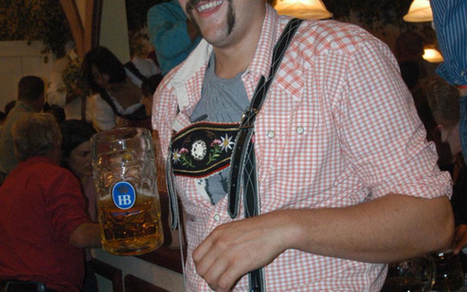 A man, decked out in traditional lederhosen, soaks in the fun at one of the famed beer halls.