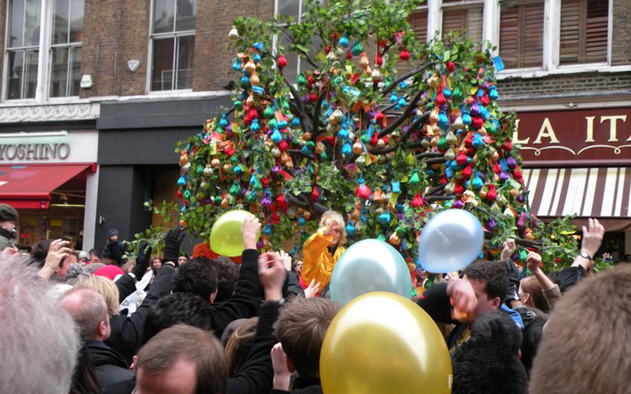 A lady tosses small goody bags taken from a decorated tree to onlookers in the streets of Chinatown in London as part of the many activities at the Chinese New Year festival.
