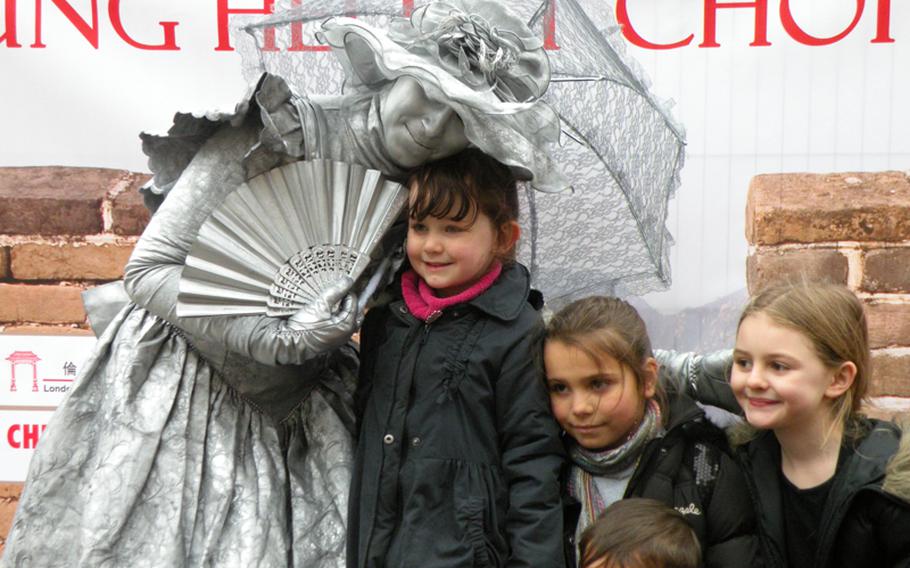 A silver-painted mime poses for pictures with some children at the 2011 Chinese New Year celebration in London on Feb. 6.