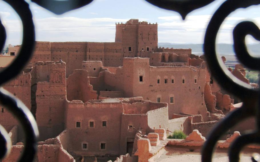 Casbah Taorirt in Ouarzazate, as seen through metalwork covering one of its windows, is a series of walls, towers and passageways. A casbah is a fortress or castle.
