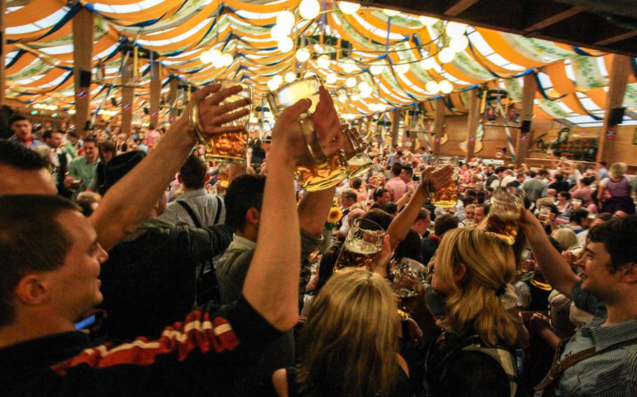 Revelers at the 2012 Oktoberfest in Munich raise their glasses to a drinking song in the Pschorr Braeurosl tent.