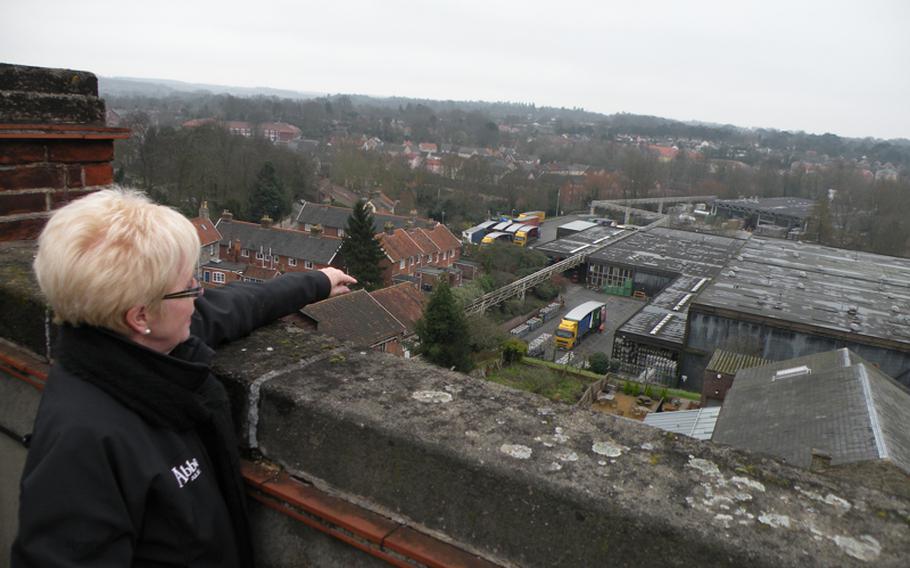 Maureen Swindles, a tour guide for the Greene King Brewing Co., points out various points of interest on the brewery grounds and the surrounding town of the Bury St. Edmunds, from atop the brewery building.