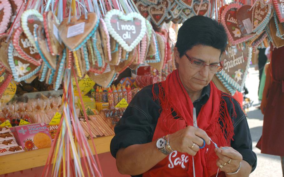 An Oktoberfest vendor ties ribbon on a lebkuchenherz, a heart-shaped gingerbread cookie popular at the annual festival. 