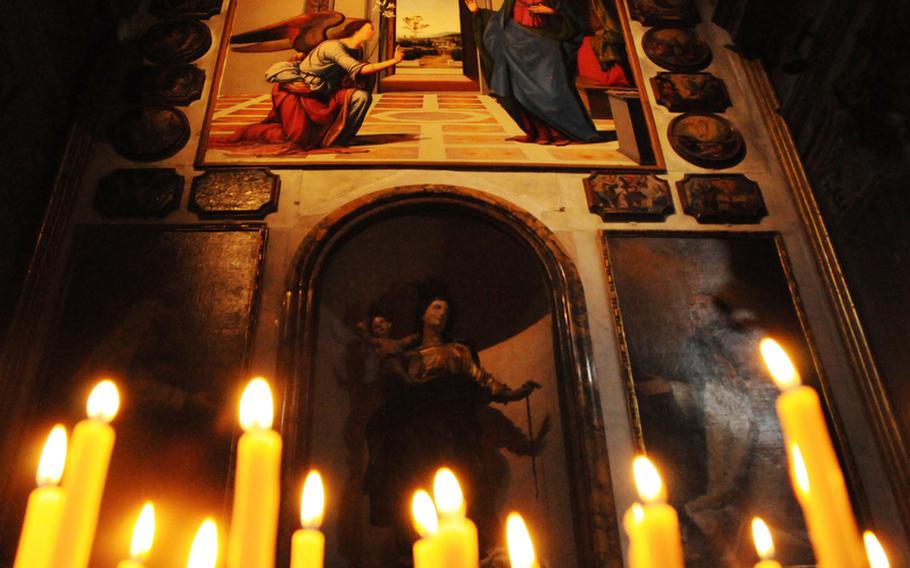 Prayer candles burn before a 16th century painting depicting the Annunciation inside the Basilica Cathedral of Santa Maria Assunata in Volterra, Italy.