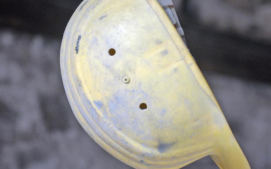 A steel worker's hat hangs from a historical workshop at Stöffel Park in Enspel, Germany. The workshop, built from 1903 to 1912, contains machine parts and offers realistic sound effects, transporting visitors back to the early 1900s.