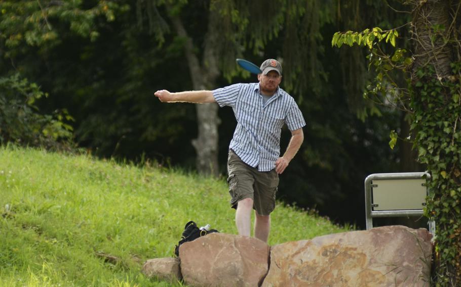 Matt Millham tees off from a brick-and-sandstone tee box at Dynamikum disc golf course.