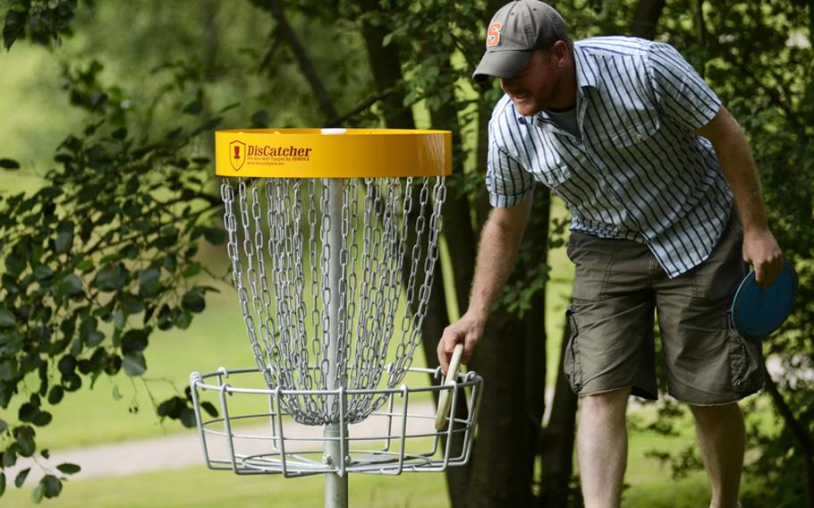 Matt Millham grabs a disc from a new DisCatcher basket at the Dynamikum disc golf course in Pirmasens, Germany.