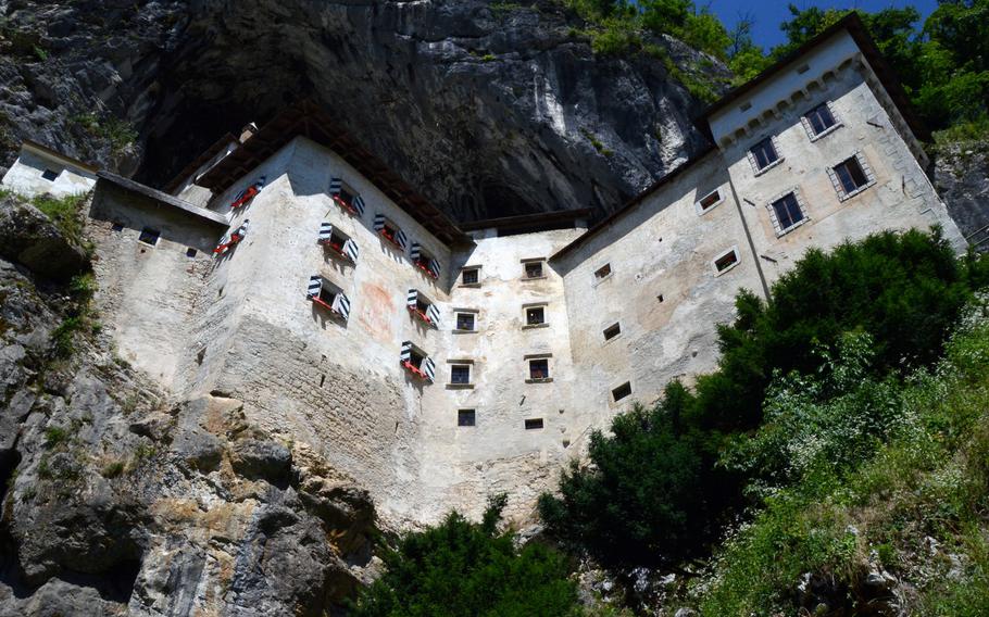 A view of Predjama Castle near the entrance to the cave located beneath the castle. The castle in Predjama, Slovenia was built into a 135- meter-tall cliff.