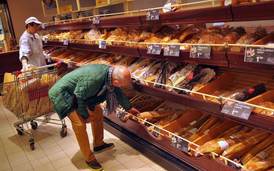A customer reaches for a baguette in Cora's bakery section. Besides baguettes and an assortment of loaves of bread, the super store in Forbach, France sells French pastries, cakes and rolls in its bakery section.