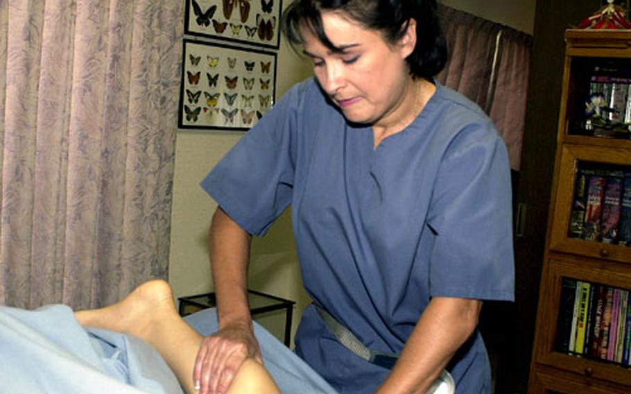 Massage therapist Sandra Hornbeek demonstrates a Swedish massage technique in her home treatment room on Junko Miyazaki, who is also a massage therapist. Both serve clients at Sasebo Naval Base.