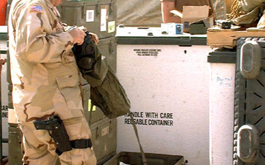Sgt. 1st Class Timothy Rothwell, left, the acting first sergeant for the 339th Combat Support Hospital, inspects a gas mask while medical supply Sgt. Brian Stormes unloads supplies.