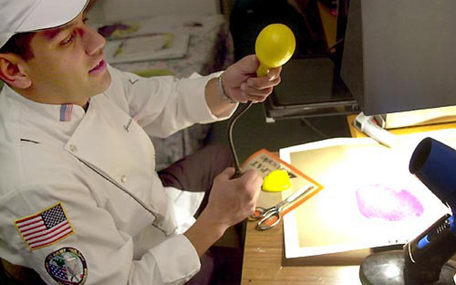 Staff Sgt. Jesse Camacho shapes a heated ball of sugar to make a decorative piece for display at the Culinary World Cup.