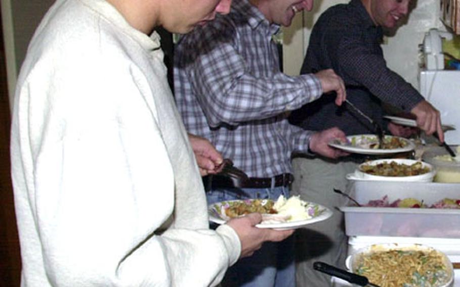 Single Marines line up to heap Thanksgiving Day meals on their plates at the Barnes home on Camp Foster, Okinawa. Staff Sgt. Scott Barnes and his wife, Nicki, make a habit of opening their homes during the holidays to single Marines who would otherwise be spending the holidays alone in the barracks.