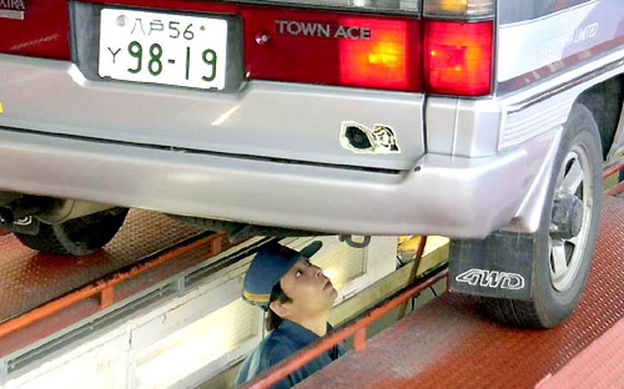 A Japanese inspector examines the underside of a van during the safety inspection at the Hachinohe Land Transportation vehicle inspection station near Misawa Air Base.