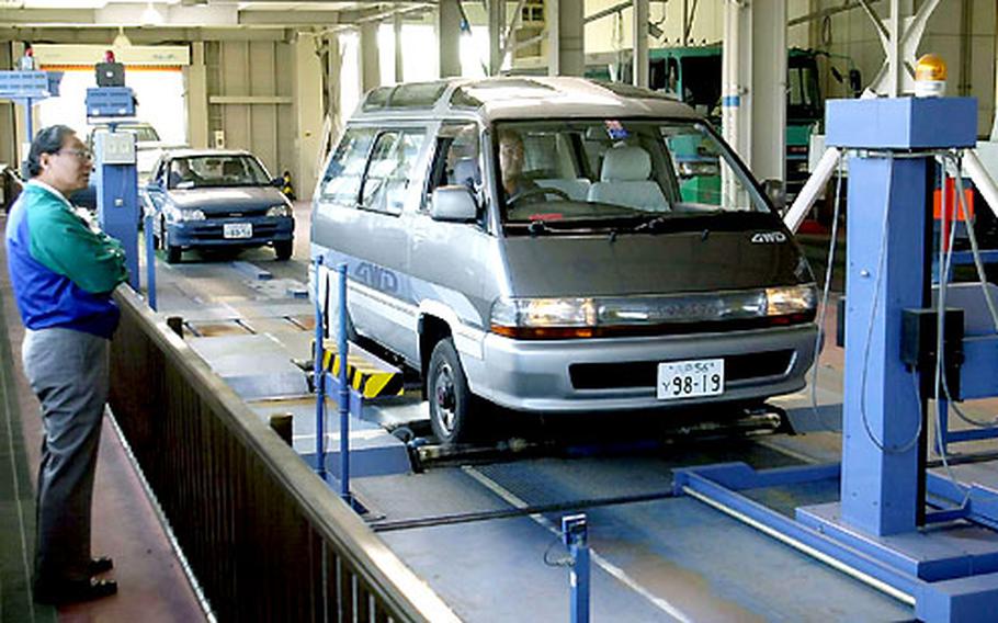 A motorist observes a van moving through the inspection line at the Hachinohe Land Transportation vehicle inspection station near Misawa Air Base, Japan. Vehicles are checked for headlight and wheel alignment, hydrocarbon emissions, integrity of brakes and many other safety requirements.