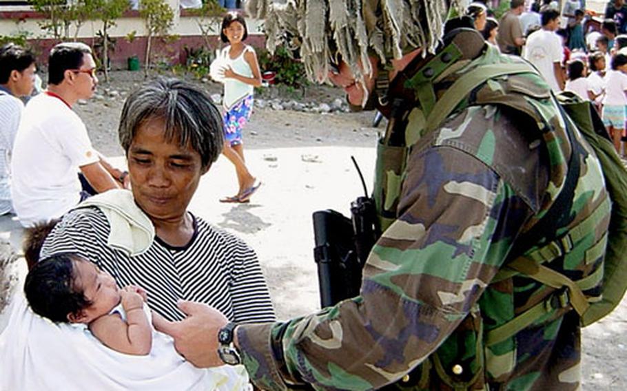 Marine Capt. Mark Clingan takes a moment to admire a local infant during the Malagutay Medical Civic Action Project in Zamboanga City, Philippines. This humanitarian program is a combined effort of the Joint U.S. Forces, Armed Forces of the Philippines and the Non Governmental Organization Tzu-Chi in direct support of Operation Enduring Freedom — Philippines.