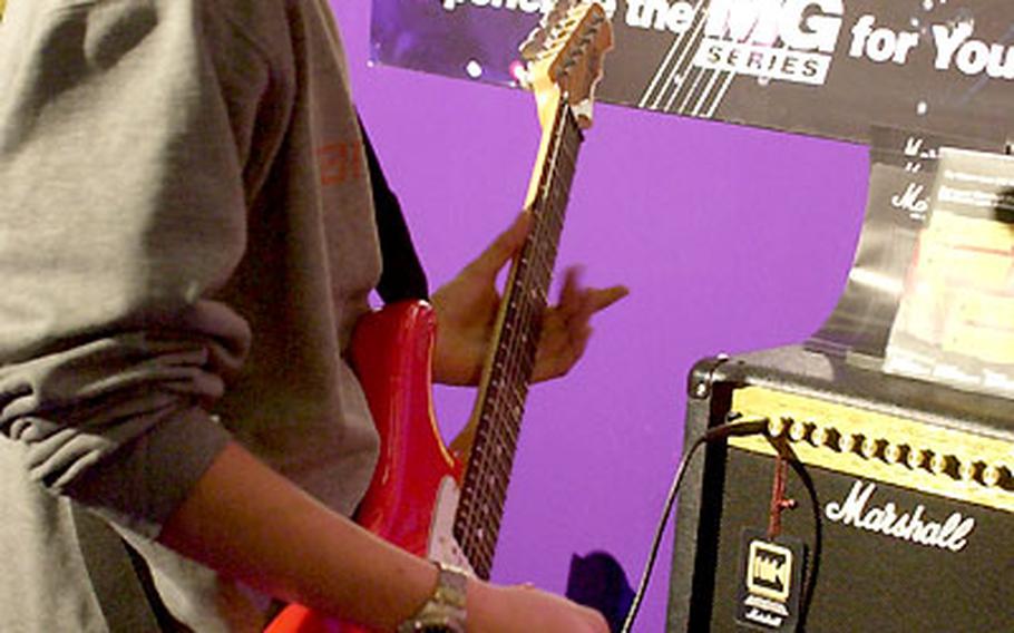 A visitor to Musikmesse 2003 finds out what an electric guitar sounds like through a Marshall amplifier.