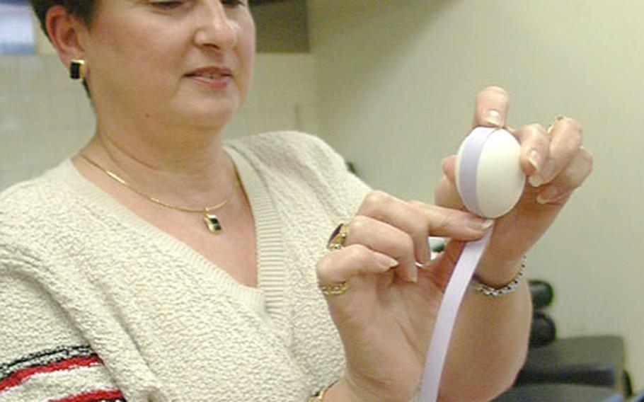 Robertta Uhl demonstrates to her craft class how to apply colored paper to an empty chicken egg.