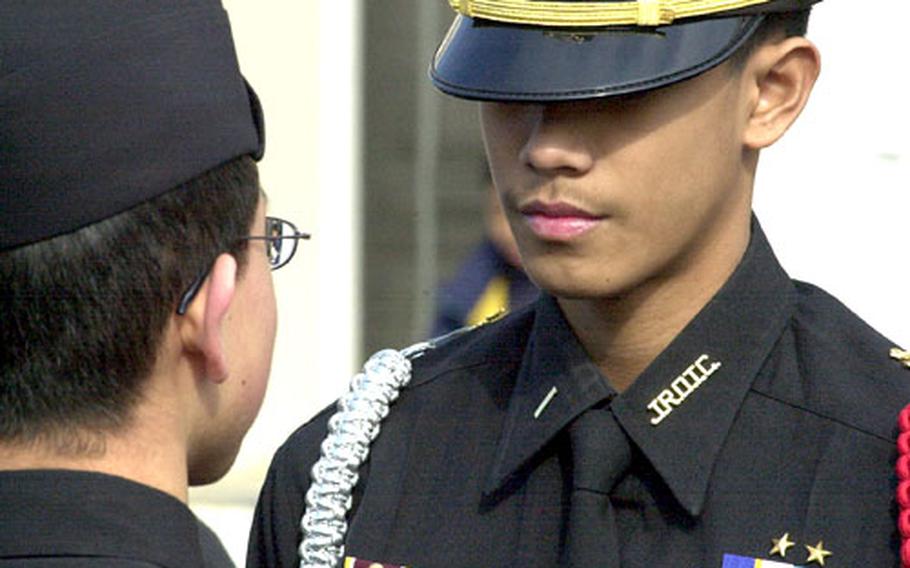 Ervin Mercado performs a personnel inspection a junior cadet on the Kinnick High School courtyard.