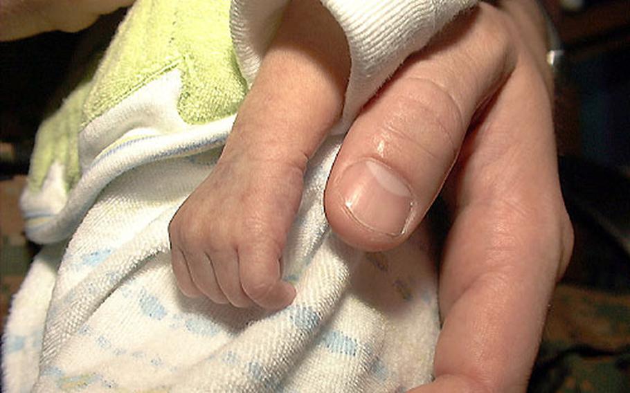 Evan Tattersall’s curled fingers are tiny in stark contrast to those of his father, Marine 1st Lt. Brandon Tattersall.