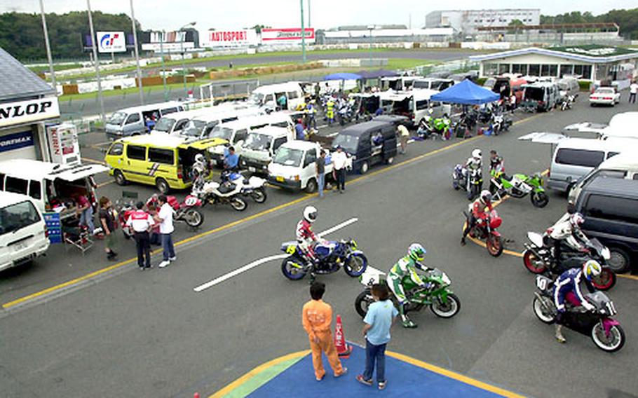 Japanese motorcyclists make adjustments and wait for their turn to race around the track at Tsukuba Circuit.