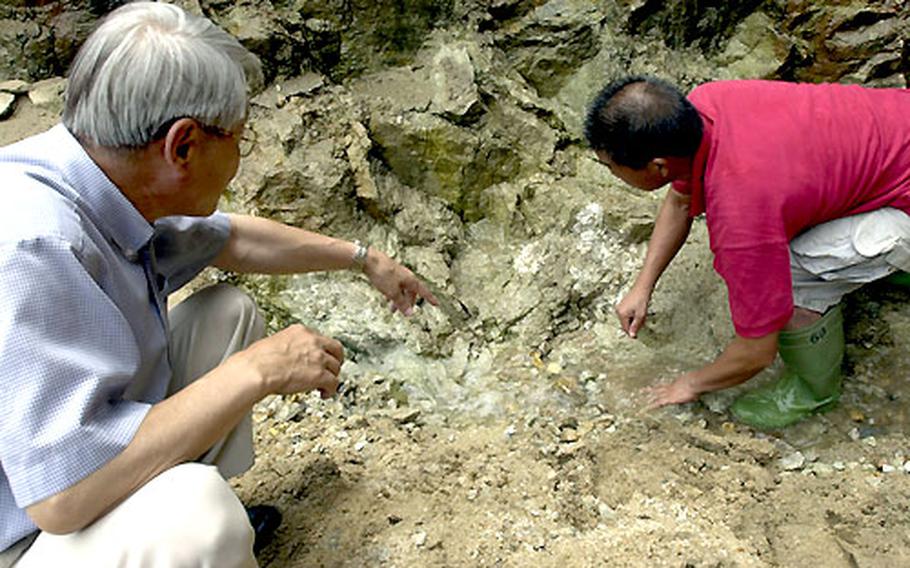 Invasion Tunnel Hunters Yoon Yo-kil and Ha Jin-soo examine rocks at the bottom of a massive pit.
