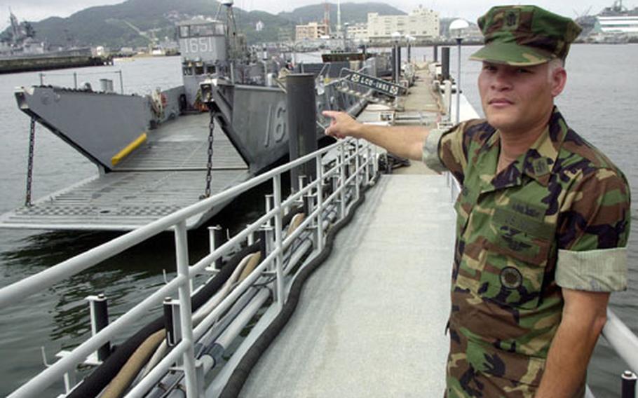 Chief Petty Officer Howard Bowen, officer in charge of Assault Craft Unit One, detachment Sasebo, points out Landing Craft Utilities, such as LCU 1651 berthed in the Juliet Basin. The berthing, heads, galley, engine room and other spaces are located below the water line.
