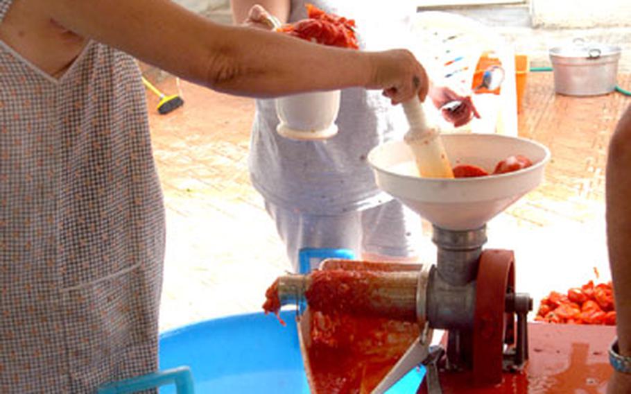 Caterina Palumbo and her daughter, Carmela, pour the cooked San Marzano tomatoes through a grinder.