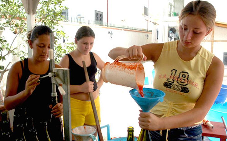Angelina Palumbo, 16, right, pours tomato sauce into wine bottles while her sister, Stefania, 13, bottles it, sealing it from any outside air. Looking on is their cousin, Caterina Pollio, 12.