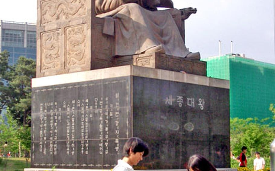 Two visitors examine the sundial at the statue of King Sejong in Yeouido Park.