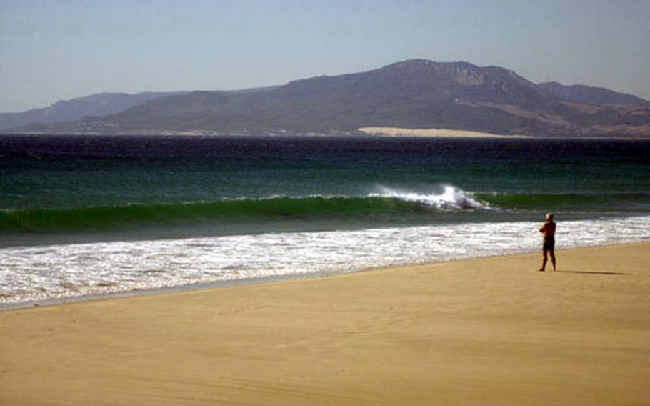 A lone man stands and admires the view from the beach near Tarifa, Spain.